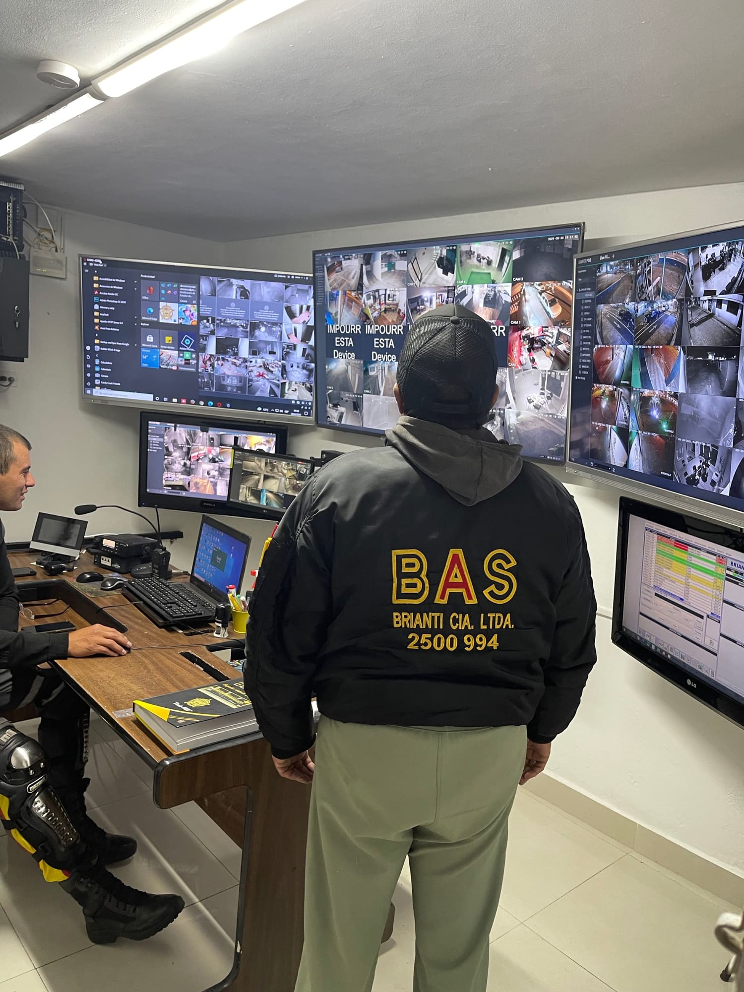 Operadores de la central de monitoreo de Seguridad BAS frente a un muro de pantallas con las cámaras de los clientes.